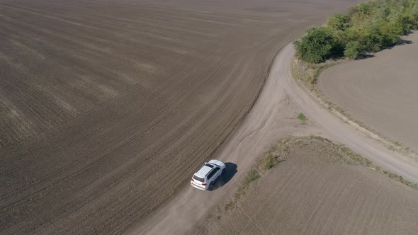 Car Rides on Road Between Fields with Cultivated Soil in Fall alt