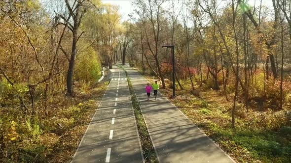 Man and Woman Jogging in Autumn Park in the Morning alt