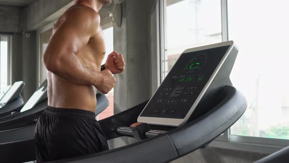 Muscular man running on treadmill at gym