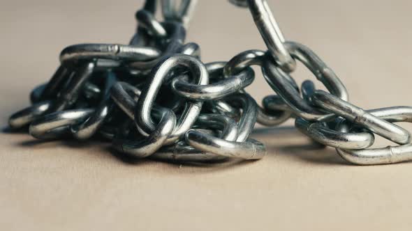 Metal Iron Chain Slowly Falls on a Wooden Table alt