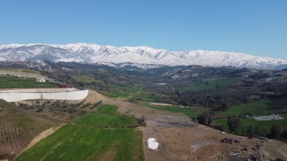 view of snowy mountains over greenhouses near city alt