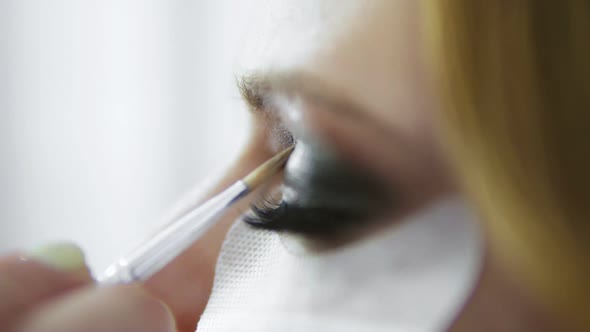 Makeup Artist Applying Eyeshadow on Eyelid Using Makeup Brush and Protecting Skin with White Patches alt