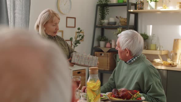 Senior Woman Giving Present to Husband at Birthday Dinner alt