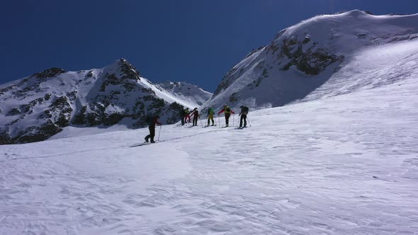 Alpine expedition of climbers and skiers walking up the mountain with ski's and poles for support