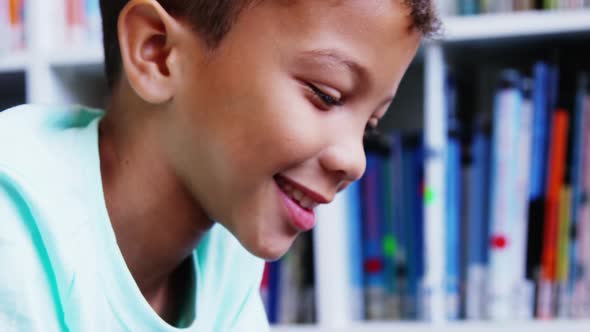 Portrait of schoolboy smiling in library at school alt
