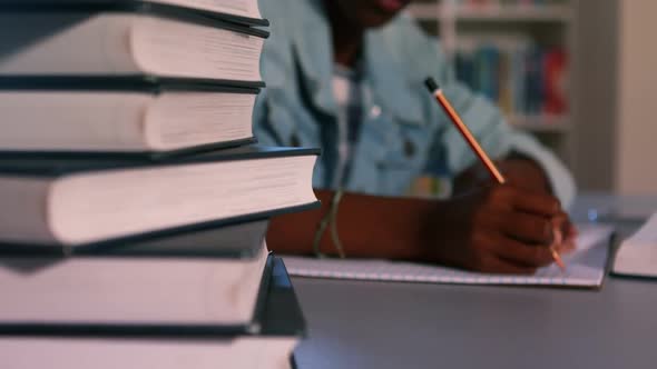 Close-up of book stack with schoolboy studying in background alt