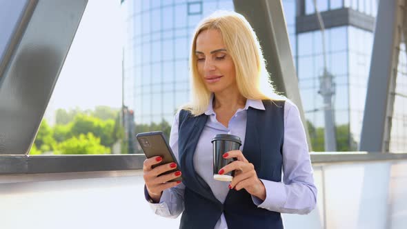 Businesswoman Standing Outside a Modern Corporate Building with Coffee Cup and Cellphone alt