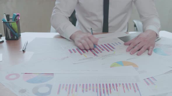  Businessman analyzes graphics while sitting in an office at a desk alt