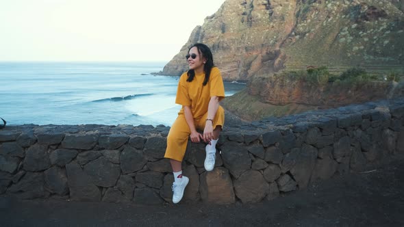 A Woman Walks Next to the Ocean Enjoying the Calm Scenery Against the Background of the Volcanic alt