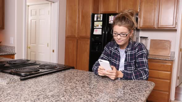 Young woman using smart phone in kitchen at home