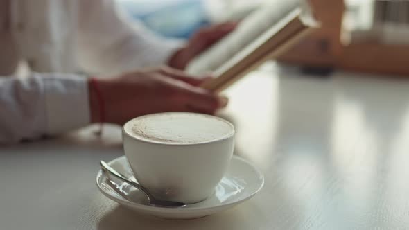 A Cup Of Hot Fresh Cappuccino In A White Dish Stands On A White Table Against The Background Of Girl alt