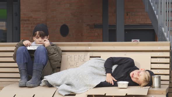 Homeless Kids Eating Outdoors and Looking Away at Strangers alt