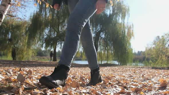 Female Legs Walking on Fallen Autumn Leaves in the Park in Slow Motion alt