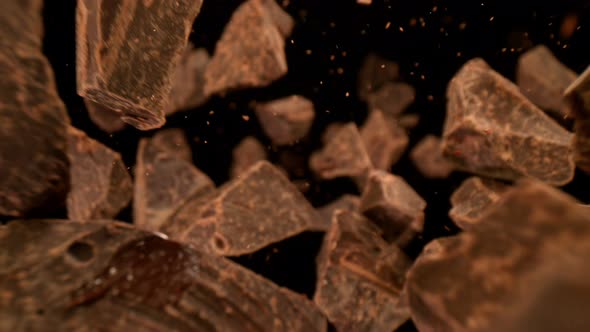 Super Slow Motion Detail Shot of Falling Raw Chocolate Chunks on Black Background at 1000Fps alt