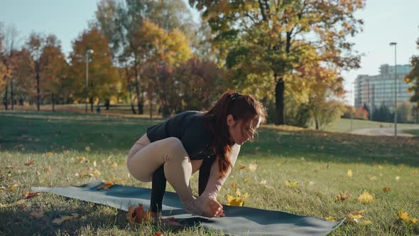 Young Woman Doing Arm Pressure Yoga Poses in Sunny Autumn Park on a Yoga Mat