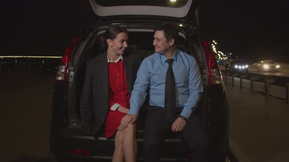 Man Flirting with Businesswoman in Car at Night alt