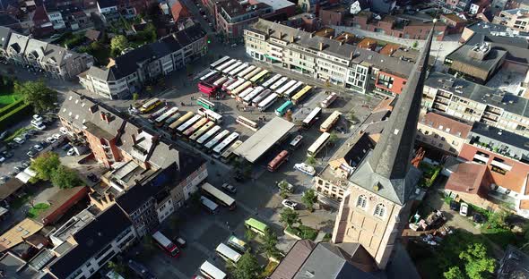 An aerial shot of busses gathering on a town square with the church dominating the view. alt