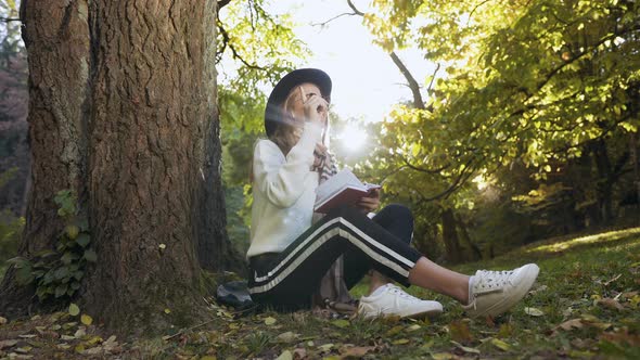 Thoughtful Young Woman Making Some Note in Her Notebook  alt