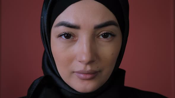 Close Up of Face of Young Muslim Woman Wearing Black Hijab Standing and Looking at Camera