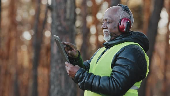 Elderly African American Forestry Engineer in Noiseisolating Headphones in Forest Old Mature Foreman alt
