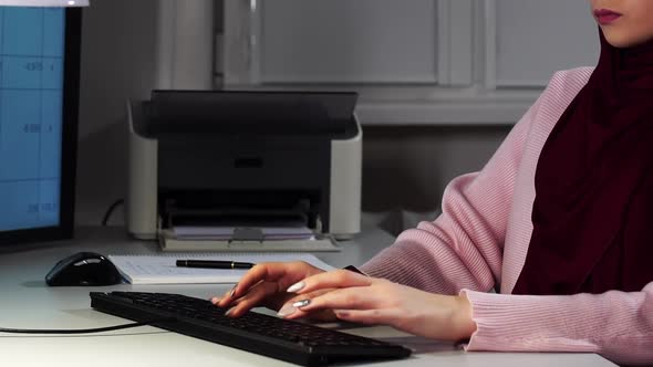 Closeup of a Muslim Manager Who Sits in Front of Computer Looking at Monitor and Types on Keyboard alt