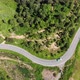 Aerial view of the road against the backdrop of green mountains along which the car is traveling. - VideoHive Item for Sale