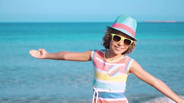 Happy Child with Open Hands against Blue Sea and Sky Background