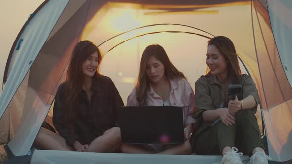 Asian young women using a laptop in a tent.