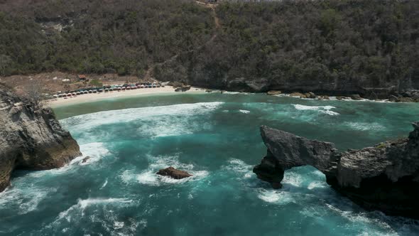 Aerial drone view of rough ocean waves, a tropical beach an archway alt