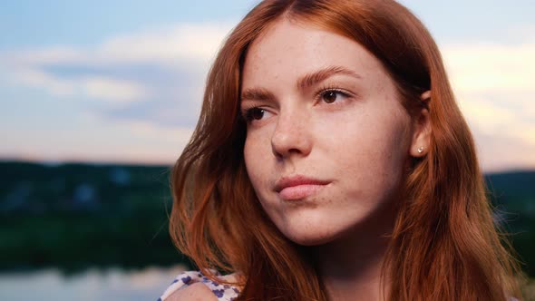Red Haired Young Girl Posing on Background of the Lake Nature at Sunset alt