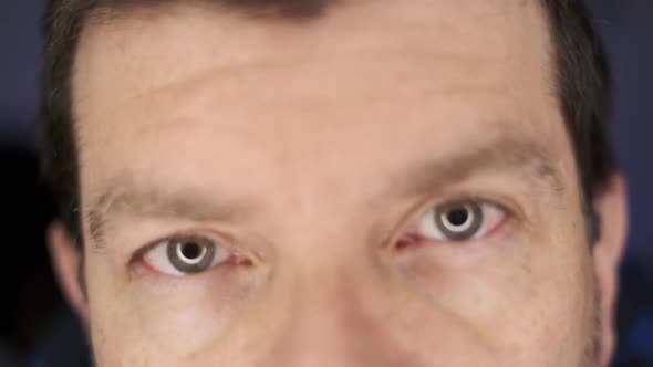 A man looking at the camera in an extreme close-up with eyes going in and out of focus, with a blue, alt