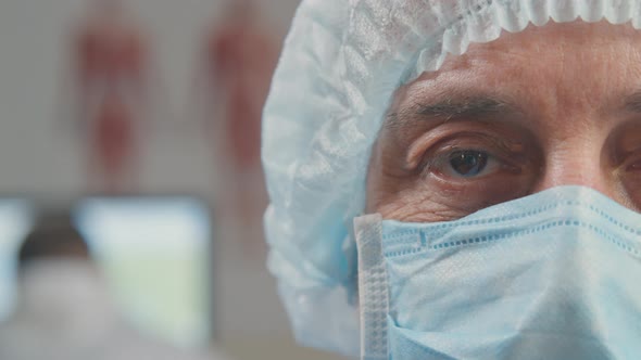 Close Shot of Mature Surgeon in Facial Mask Smiling at Camera alt
