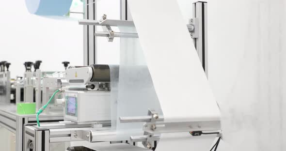 Non-woven Fabric Roll Feeding Filter Material To Machine. Making Surgical Face Mask In PPE Factory. alt