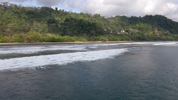 The lush, tropical nature bordering at Dominical Beach in Costa Rica on a cloudy day. Aerial wide an alt