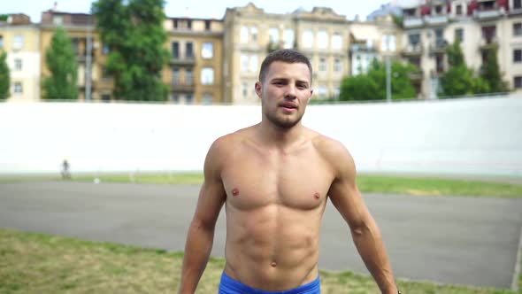 Muscular Guy with a Naked Torso in Outdoor Street Gym alt