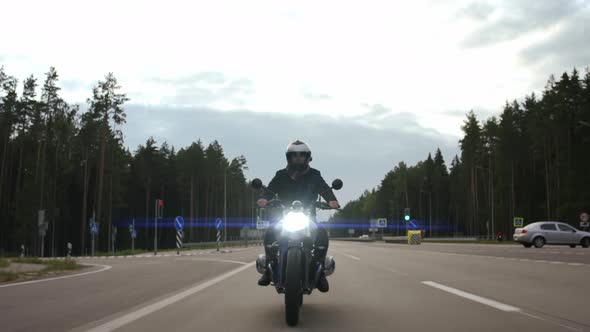 Man Riding Scrambler Motorbike on the Highway Through the Forest Front View alt