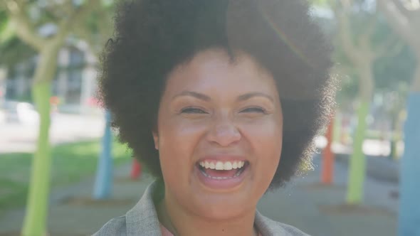 Portrait of happy plus size biracial woman smiling in park alt