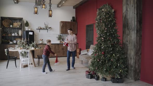 Dad Son in Festive Living Room Have Fun and Dress Each Other Santa Hats
