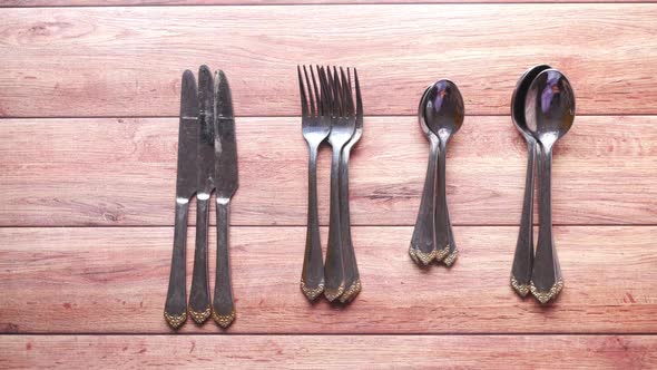 Putting Cutlery Fork with Knife and Spoon on Blue Background alt