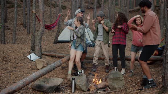 Slow Motion of Carefree Youth Tourists Dancing in Campsite in Forest Around Fire Enjoying Nature and alt