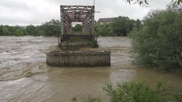 An Old Abandoned Bridge Over a River That Overflows. Stormy Water Flows. Extremely High Water Level