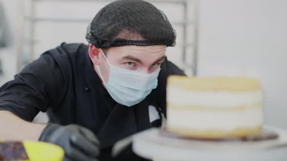 Closeup Portrait of Concentrated Cook Examining Layer Cake on Rotating Table alt