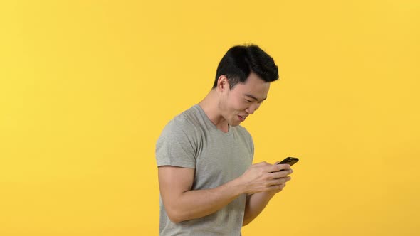 Excited fun asian man playing game on mobile phone
