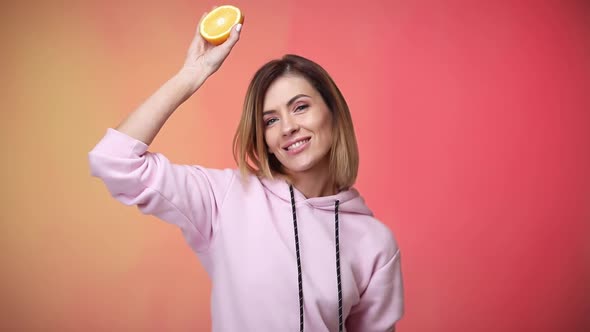 Woman in Casual Pink Clothes Holding Oranges and Dancing