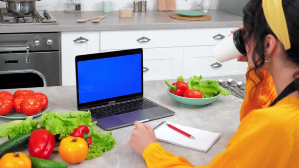 Woman in Kitchen Looking Blue Screen Mock Up Chroma Key Laptop Drinking Coffee alt