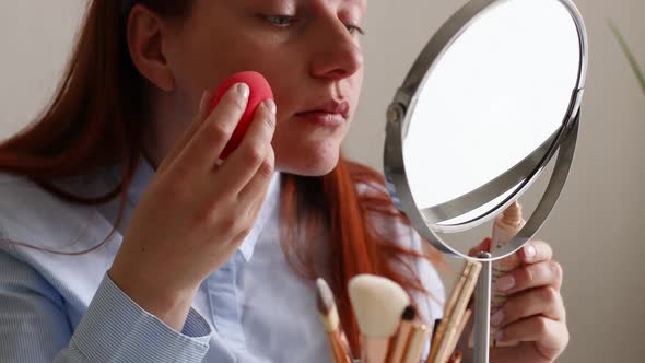 Woman Doing Makeup Put Cosmetics on Face Looking in Mirror at Home