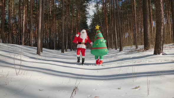 Santa Claus with a Woman Dressed in Doll Inflatable Christmas Tree Costume Happily Dancing alt