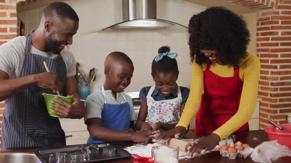 African american family wearing aprons baking together in the kitchen at home alt