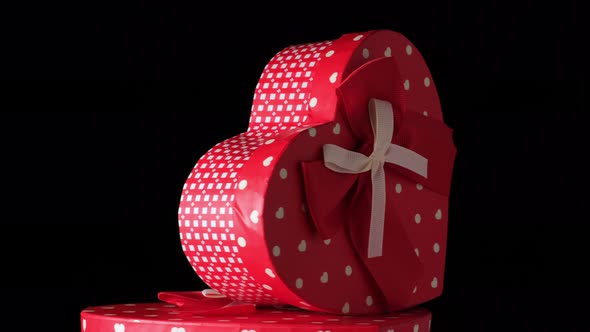 red heart-shaped cardboard box with bow on black background alt