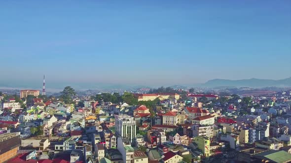 Drone Camera Moves Up Over City Against Wide Blue Sky alt